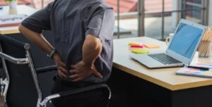 Man rubbing his back at his desk while working in an office