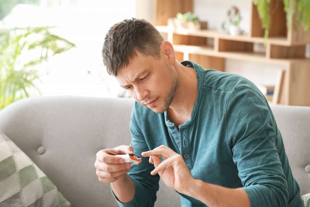 Diabetic man checking blood sugar level at home