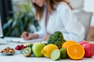 Fruit and vegetables on a table with a lady in the background